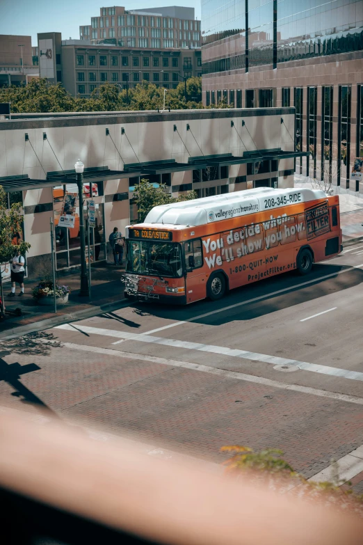 there is an orange and white bus parked at the curb