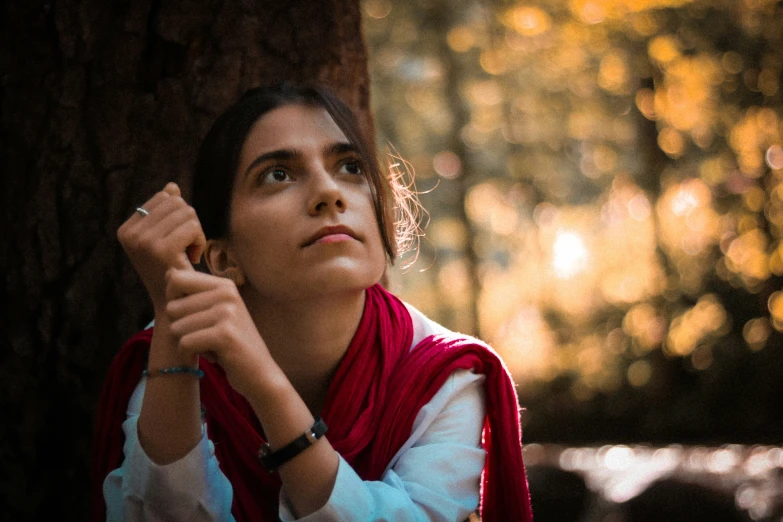 a woman wearing a red scarf looking upwards at the sky