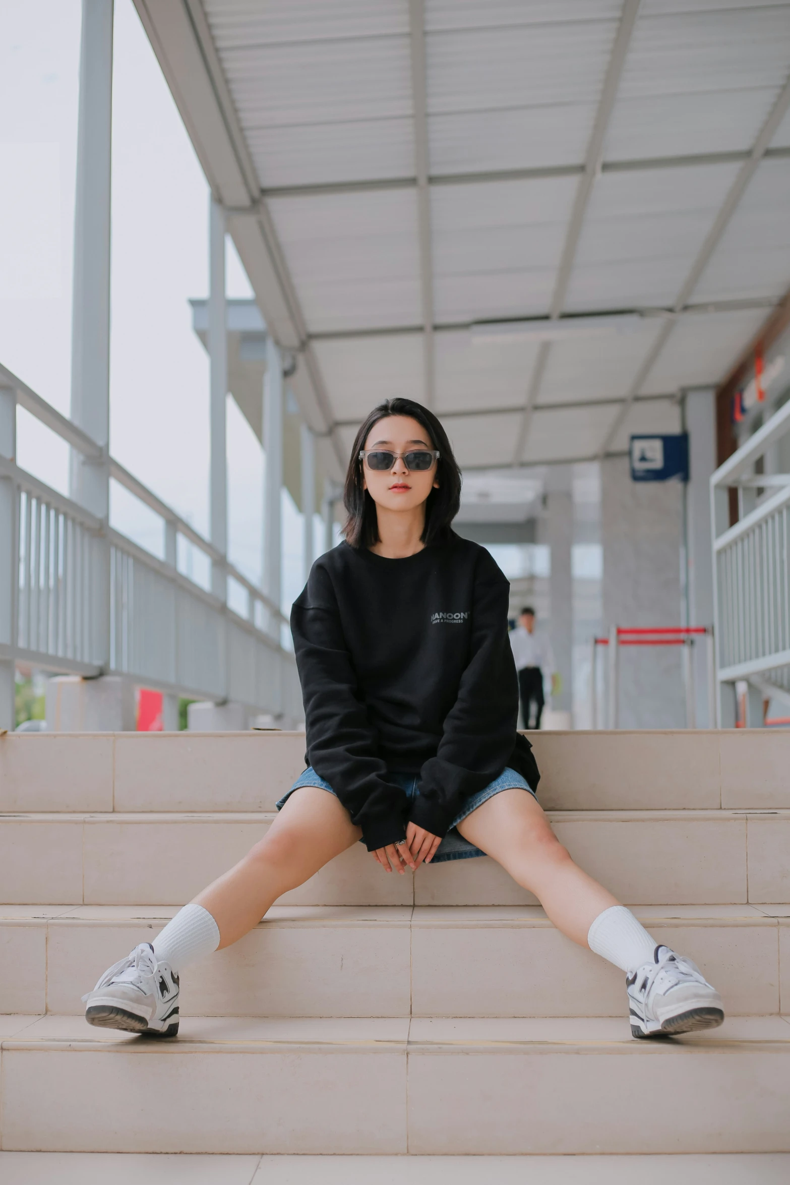 a woman wearing a black sweatshirt sits on the edge of some stairs