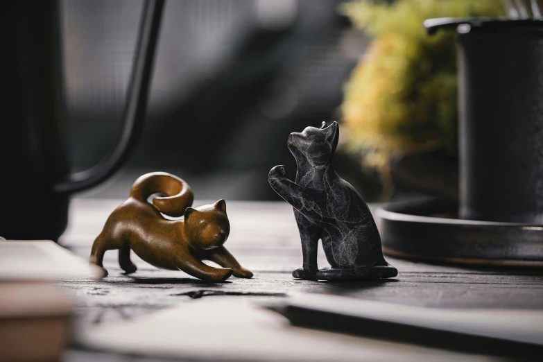 some figurines are sitting on a table with one dog and another cat