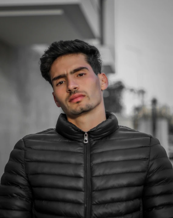 man in black jacket and white background looking away