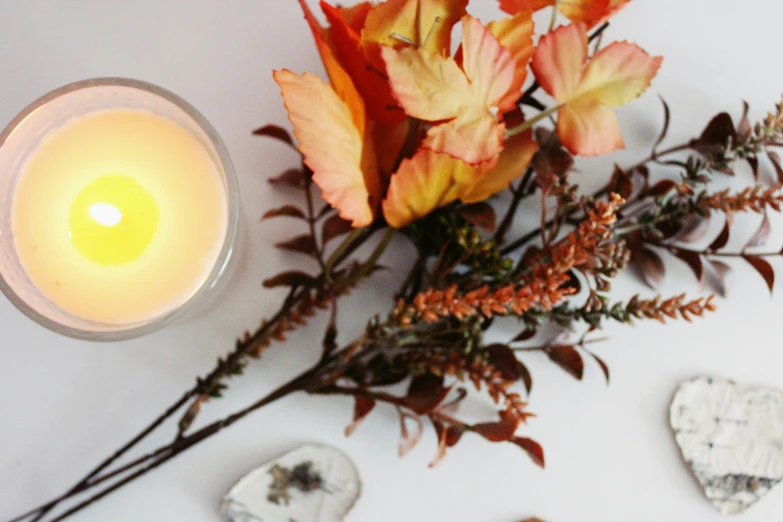 flowers and a candle placed in front of some stones