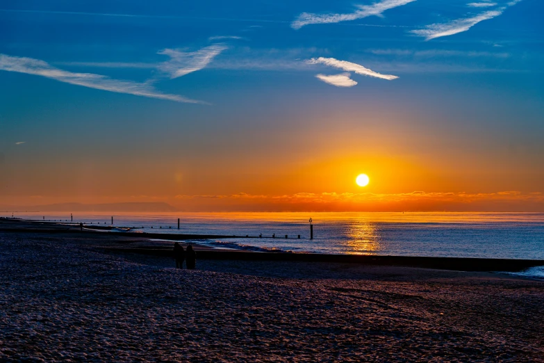 the sun set at sea, with clouds on a blue sky