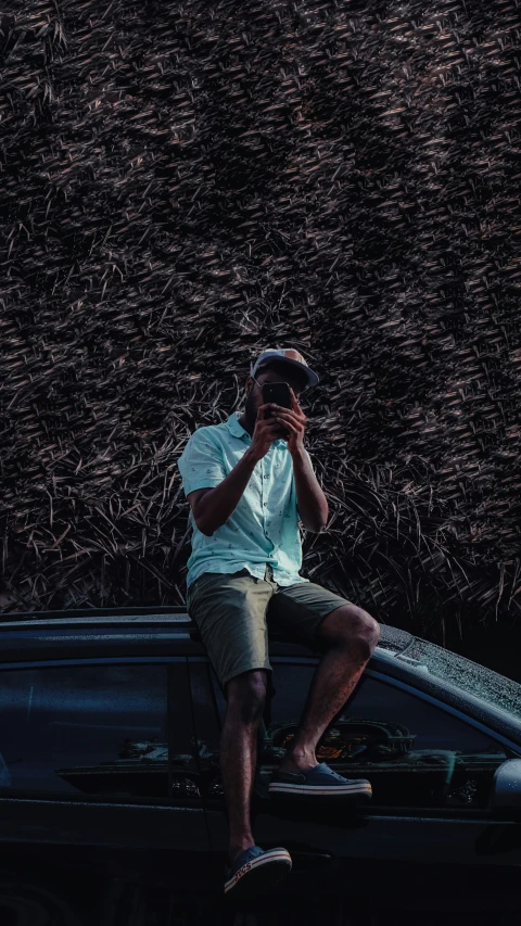 man sitting on top of a car taking a picture of himself