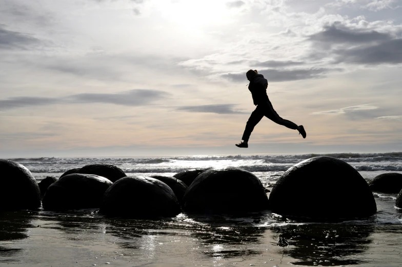 a woman jumping off rocks over a body of water