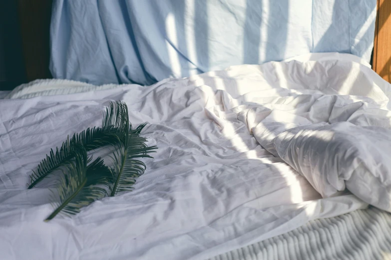 an unmade bed with a white and gray linen