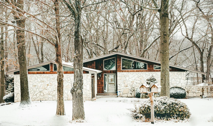 a stone cabin is surrounded by trees and snow