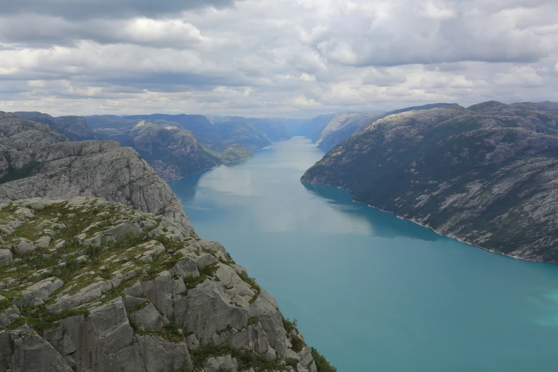 a lake with mountains behind it on a cloudy day