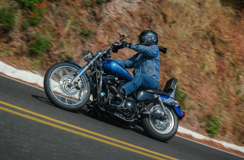 a man in blue riding on the back of a motorcycle