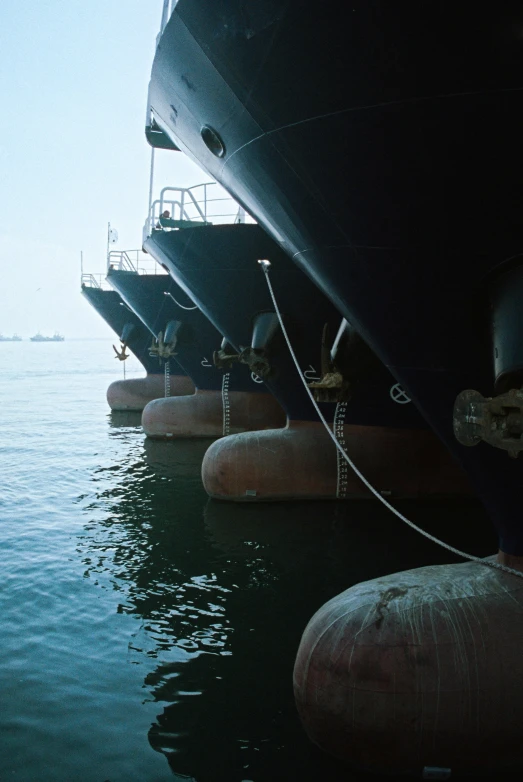 three big boats floating side by side on the water