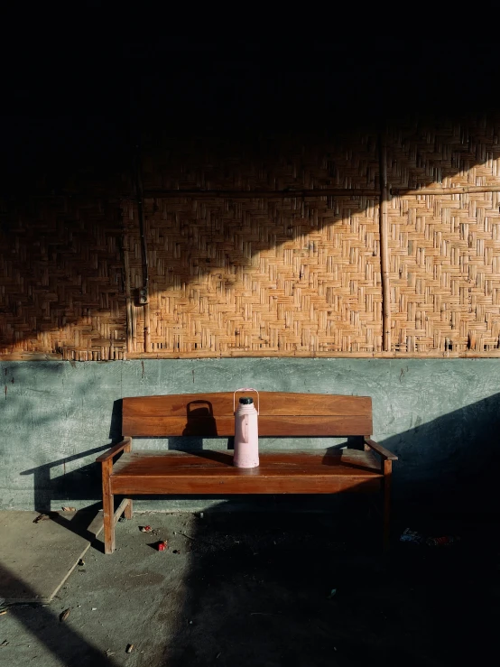 a coffee cup sits on a bench in front of a wall