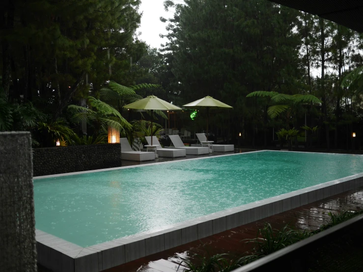 a pool surrounded by lounge chairs under umbrellas