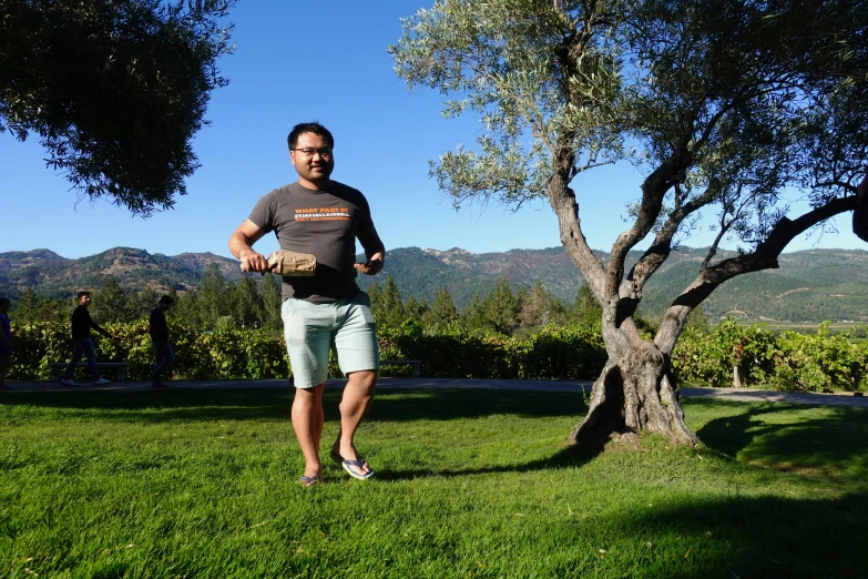 a man holding a frisbee standing on top of a lush green field