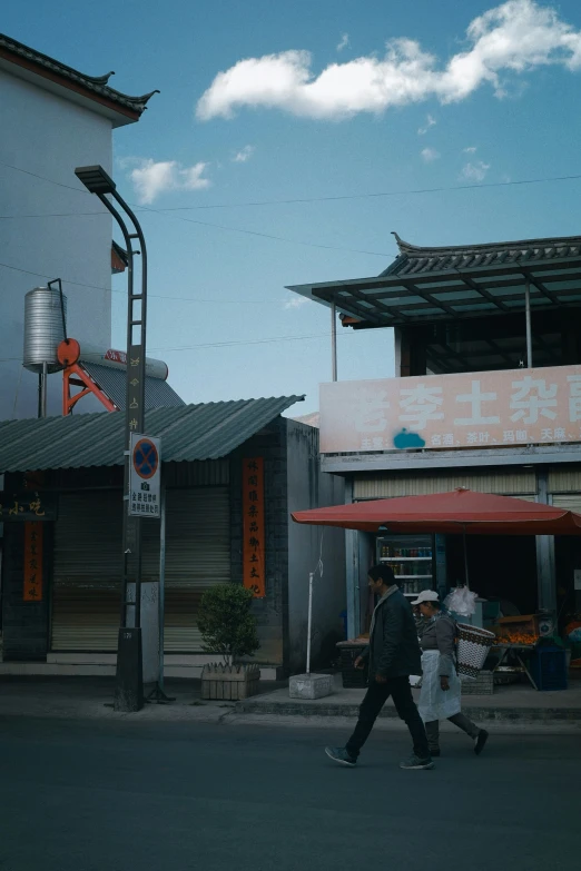 two people walking down a street near an asian restaurant