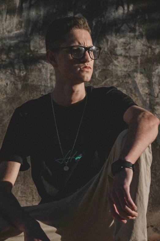 a man in a black shirt and glasses with his hand over the knee