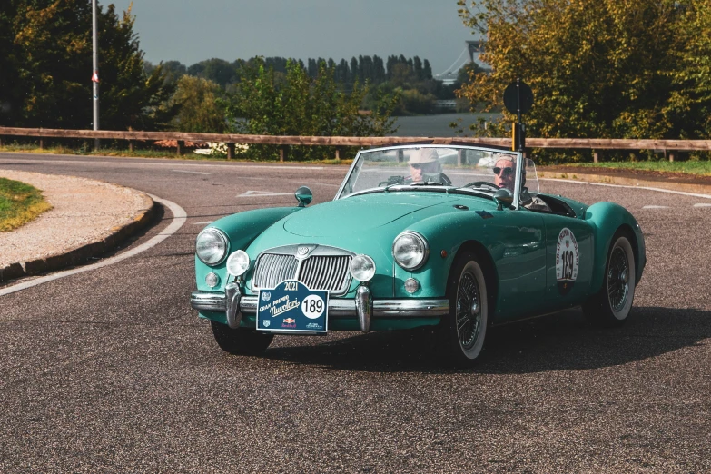 an old classic sports car is on a road