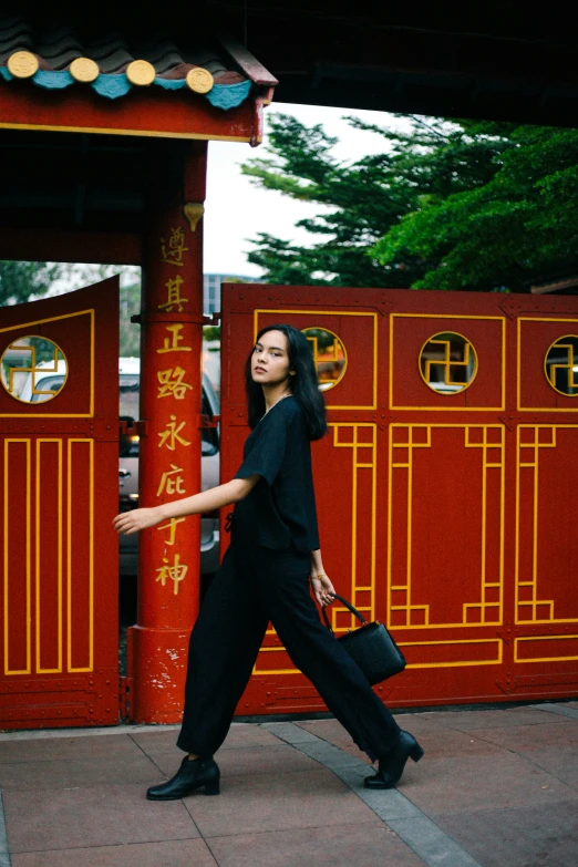 a woman in black jumpsuit carrying a suitcase