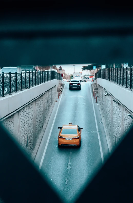 orange car driving through a city street tunnel