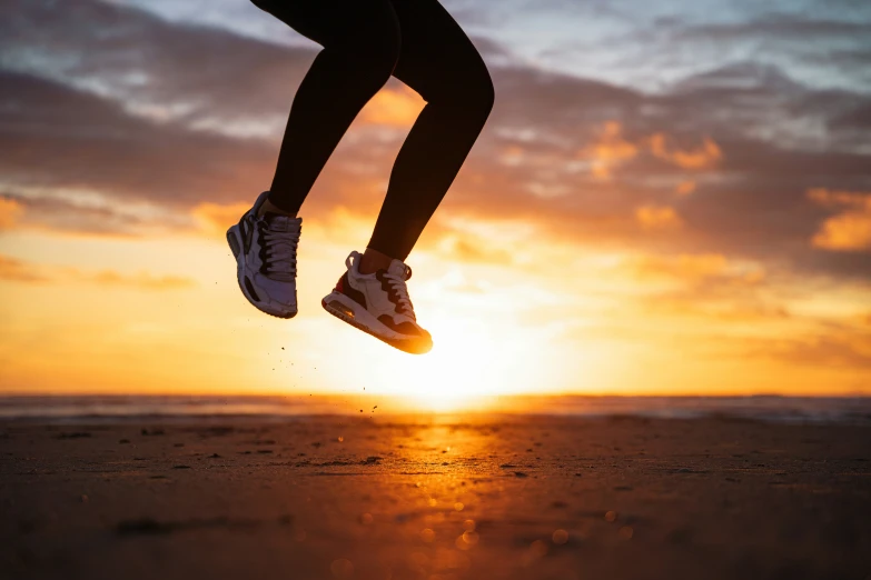 the silhouette of a woman's legs as the sun sets behind the water