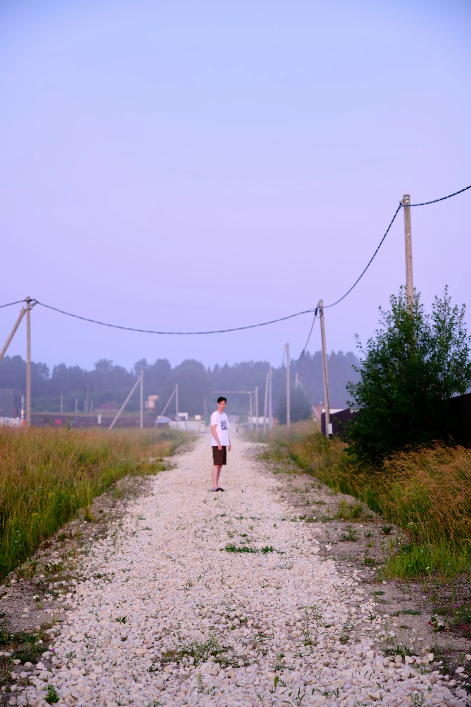 a person stands on a gravel road in the middle of nowhere