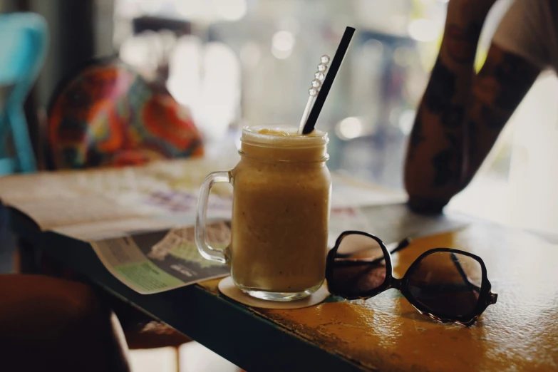 a glass cup with a straw and two sunglasses on the table