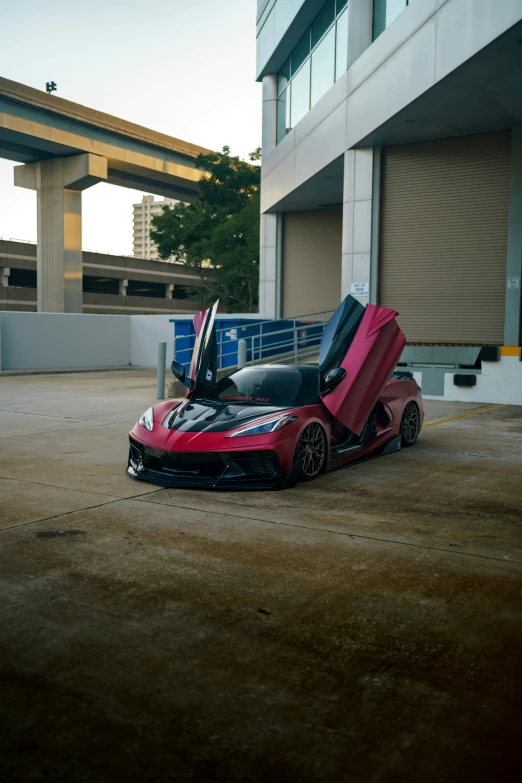 a large, red car with a hood opened parked in front of a building