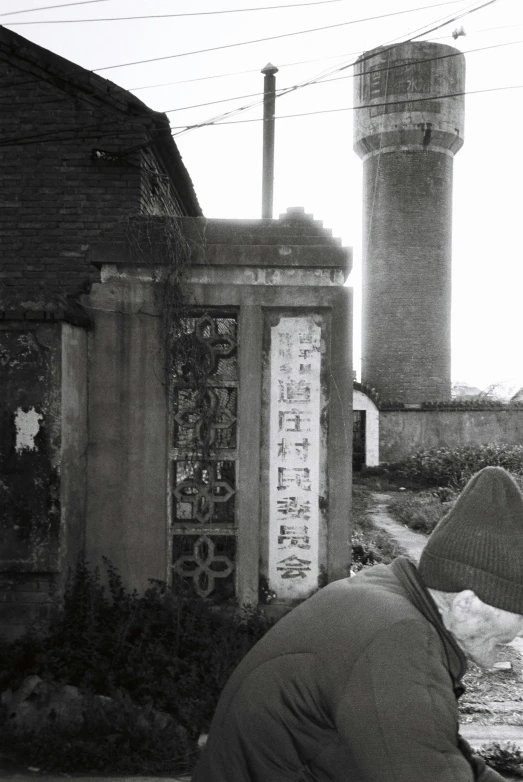 a man sits outside a tall tower near a stream