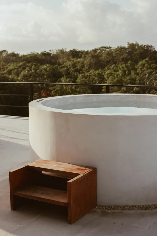 a wooden box sits on a concrete platform near a large  tub