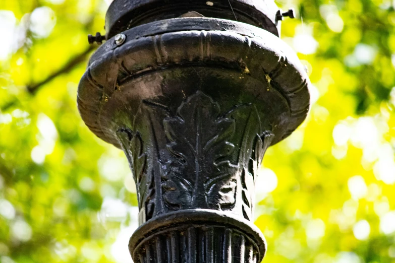 an antique lamppost stands among some green leaves