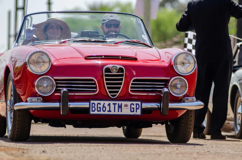 the vintage car drives down the street with people