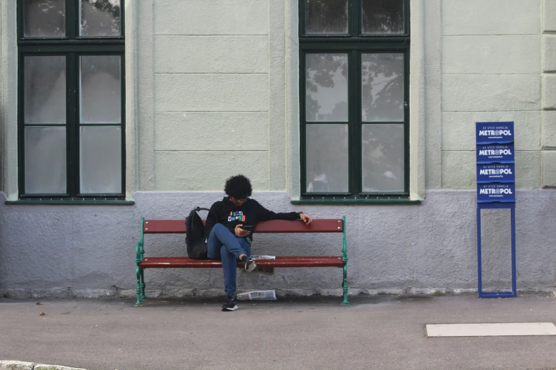 a person sitting on a bench next to a sign