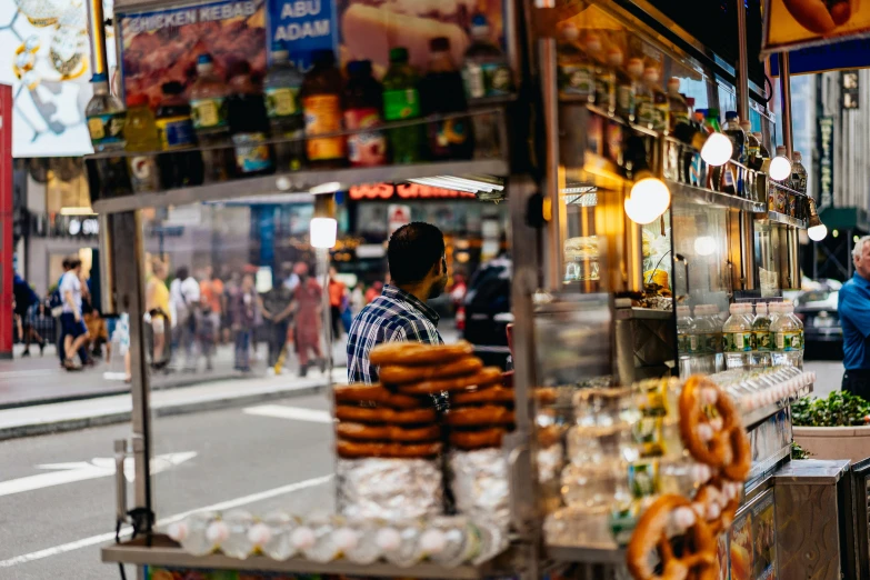 there is a man with a bagel stand in the street