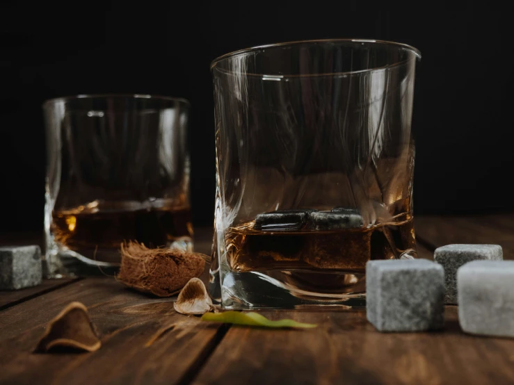 an alcoholic beverage is next to two rocks on the wooden table