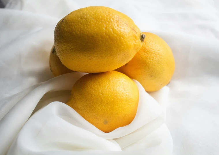 three oranges on a white blanket on a bed