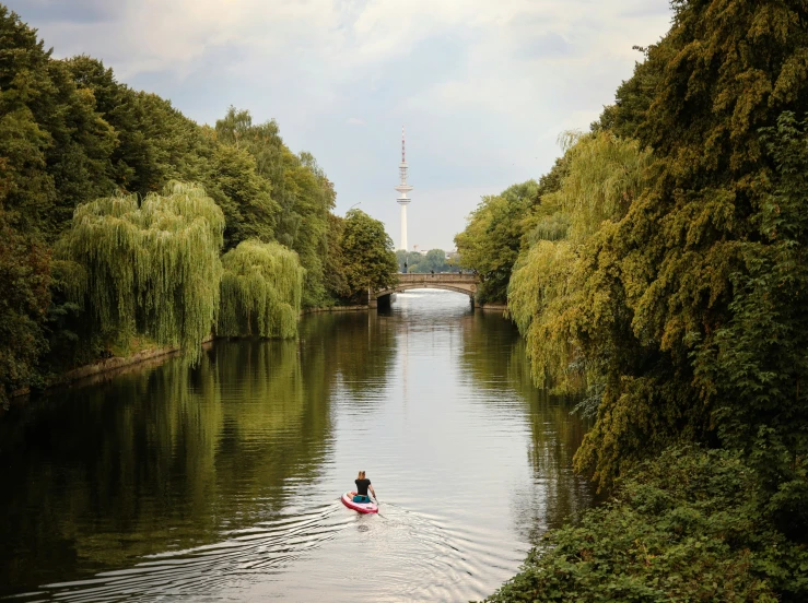 a person in a kayak paddling down a canal near trees