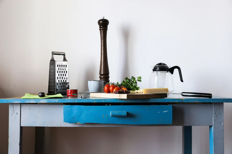 a blue table has food, salt and pepper shaker and pepper grinder