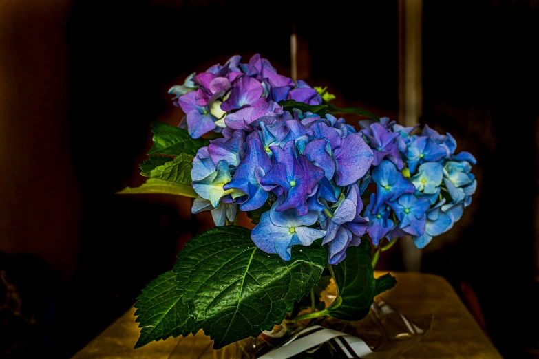 a vase full of blue and purple flowers on a table