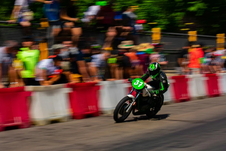 a motorcyclist speeds his motorcycle by a crowd of people