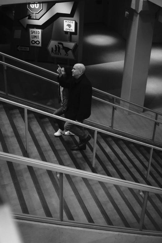 an elderly man on an escalator reading soing on his cellphone