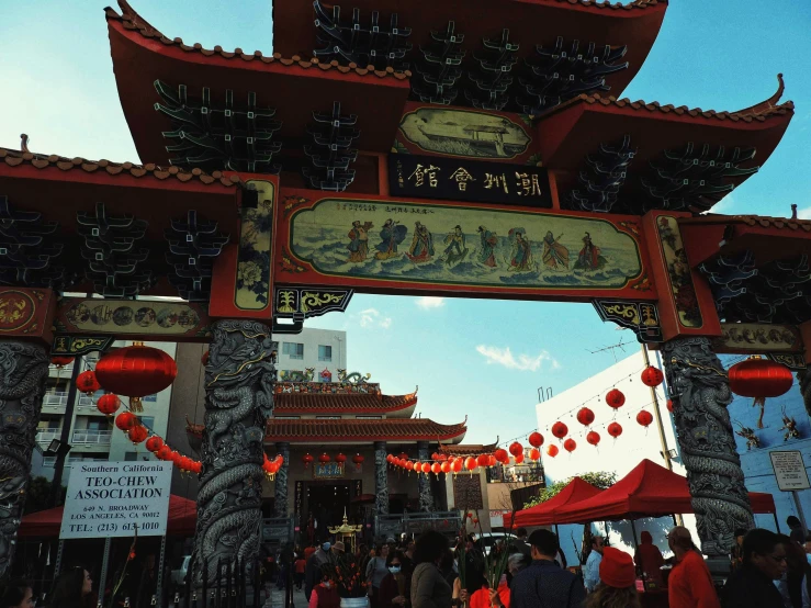 asian arch with oriental decoration on it with people walking underneath