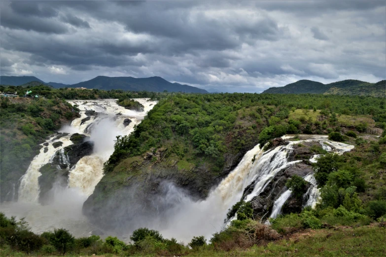 a large waterfall of water surrounded by a forest