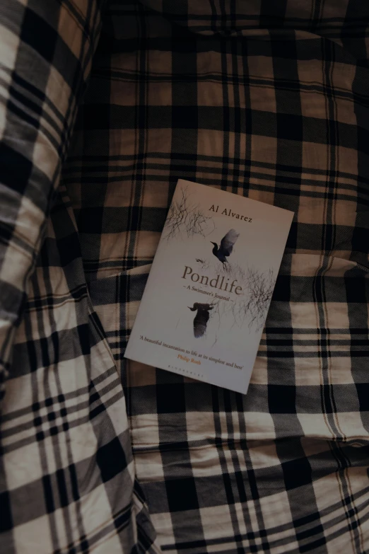 a book lying on a plaid cloth chair