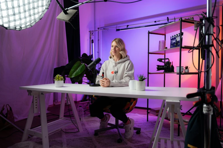 a woman sits in front of a light, behind an event set up