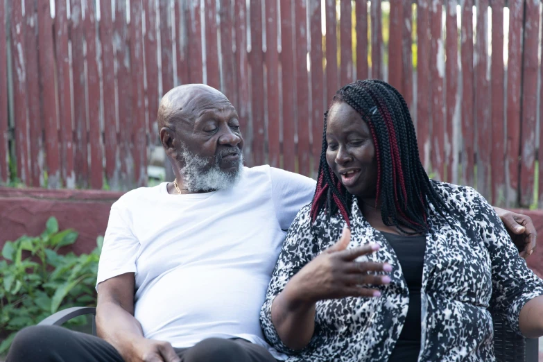 an older black couple sitting together outside