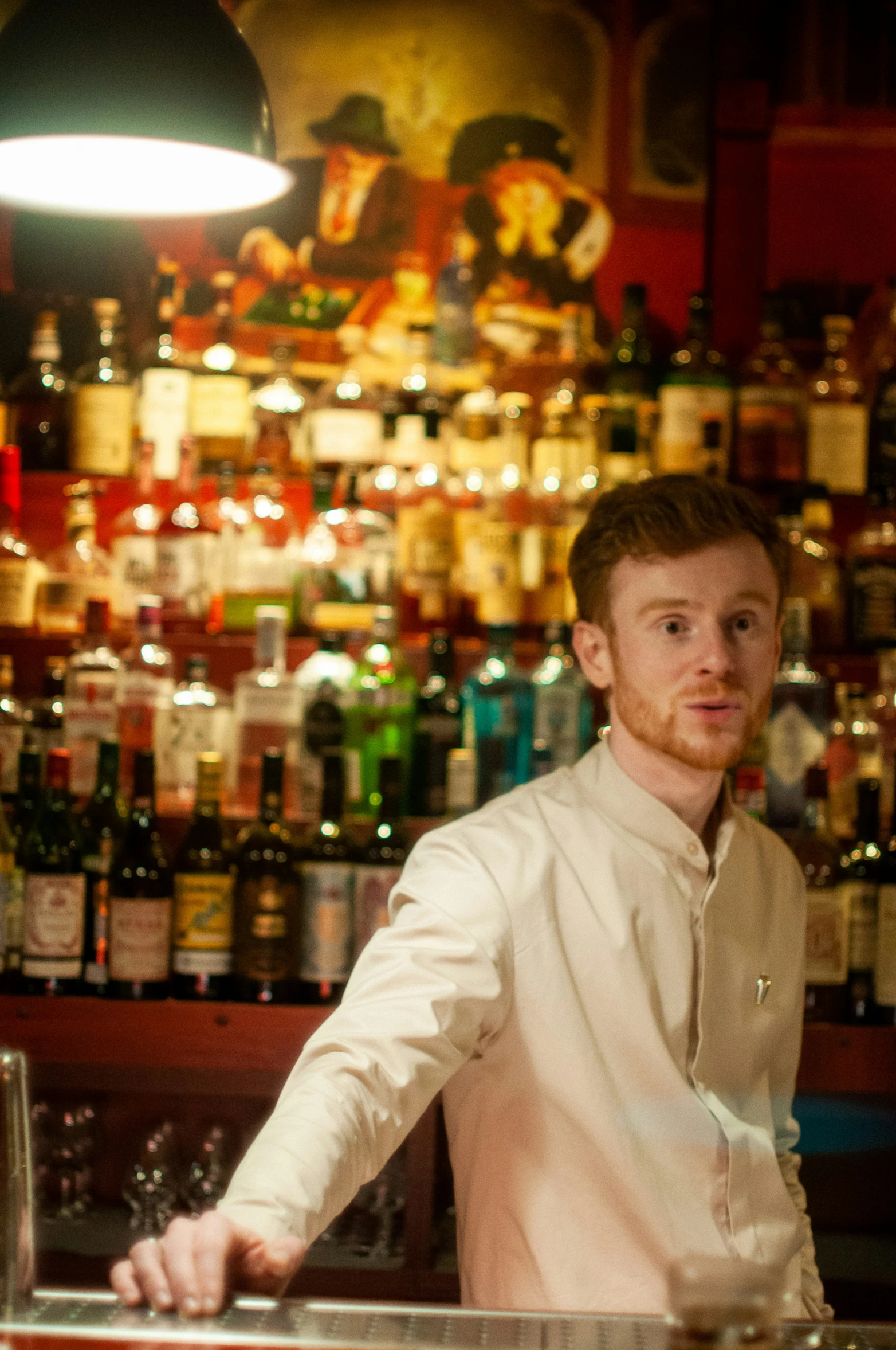 a man standing at a bar with several bottles on the wall