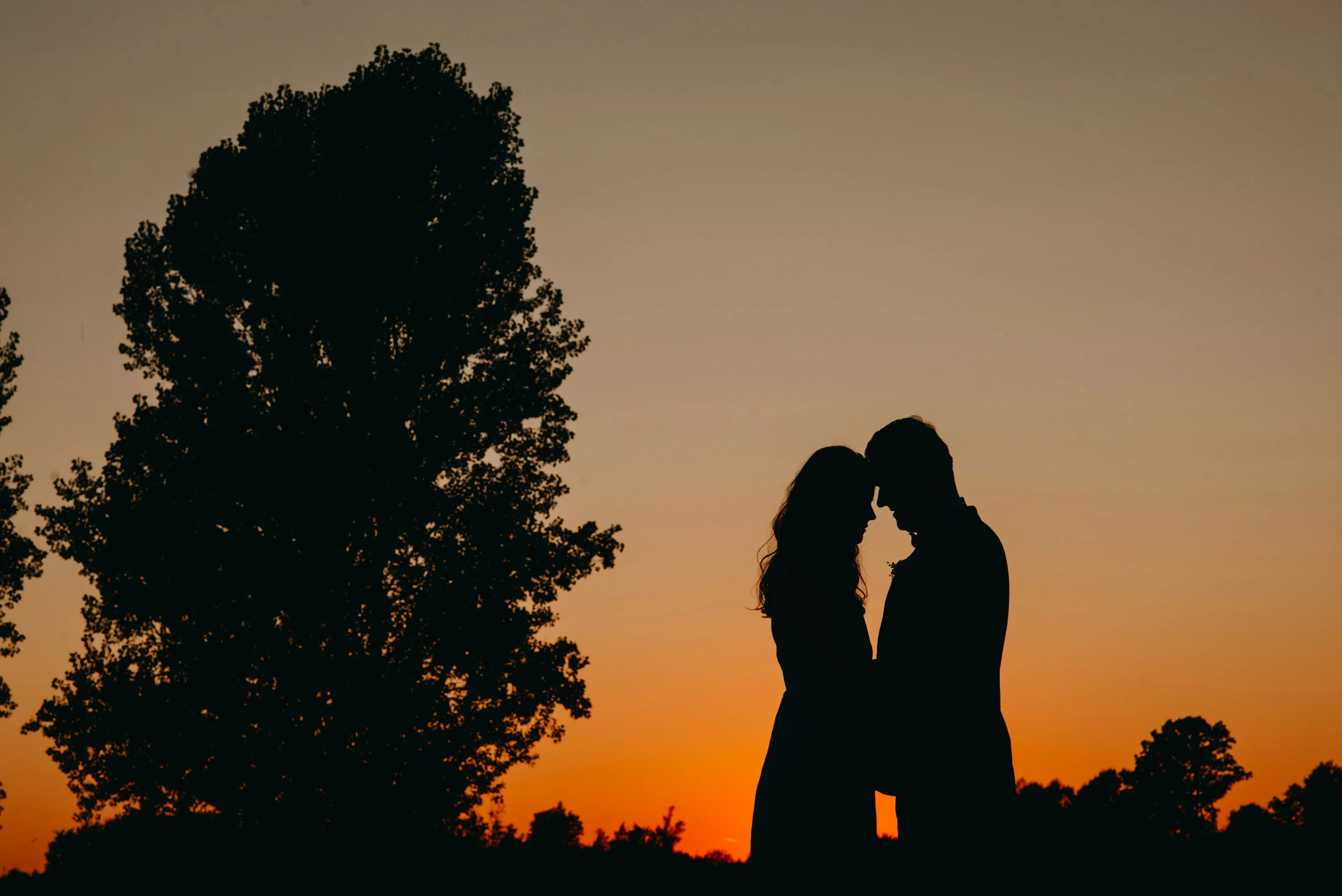 the silhouette of a couple kissing as the sun sets