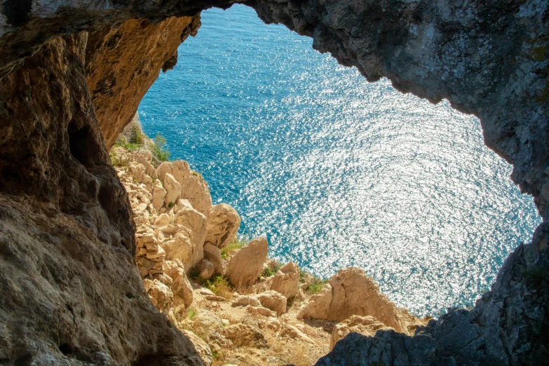 an ocean view is seen from inside a rock cave