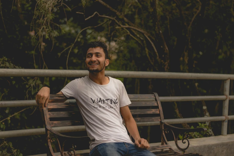 a man sitting on a park bench with trees in the background