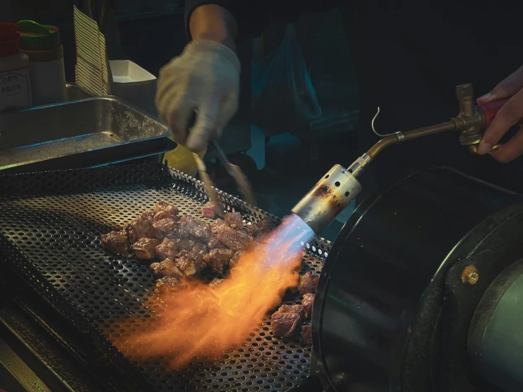 man cooking food outside on grill with tongs