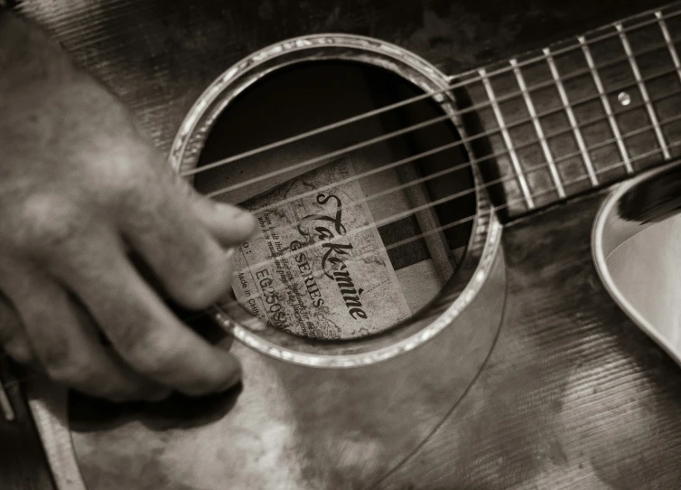 a person playing an acoustic guitar with their finger